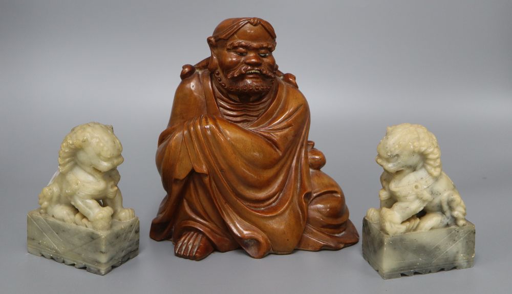 A Japanese rootwood carving of a seated elder, inset eyes and teeth and a pair of Chinese soapstone shishi, each crouched on a rectangu